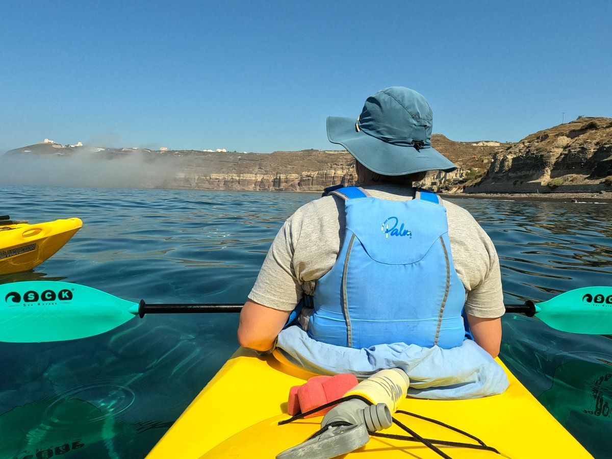 Suzie from behind sitting in front of double kayak with caldera beyond