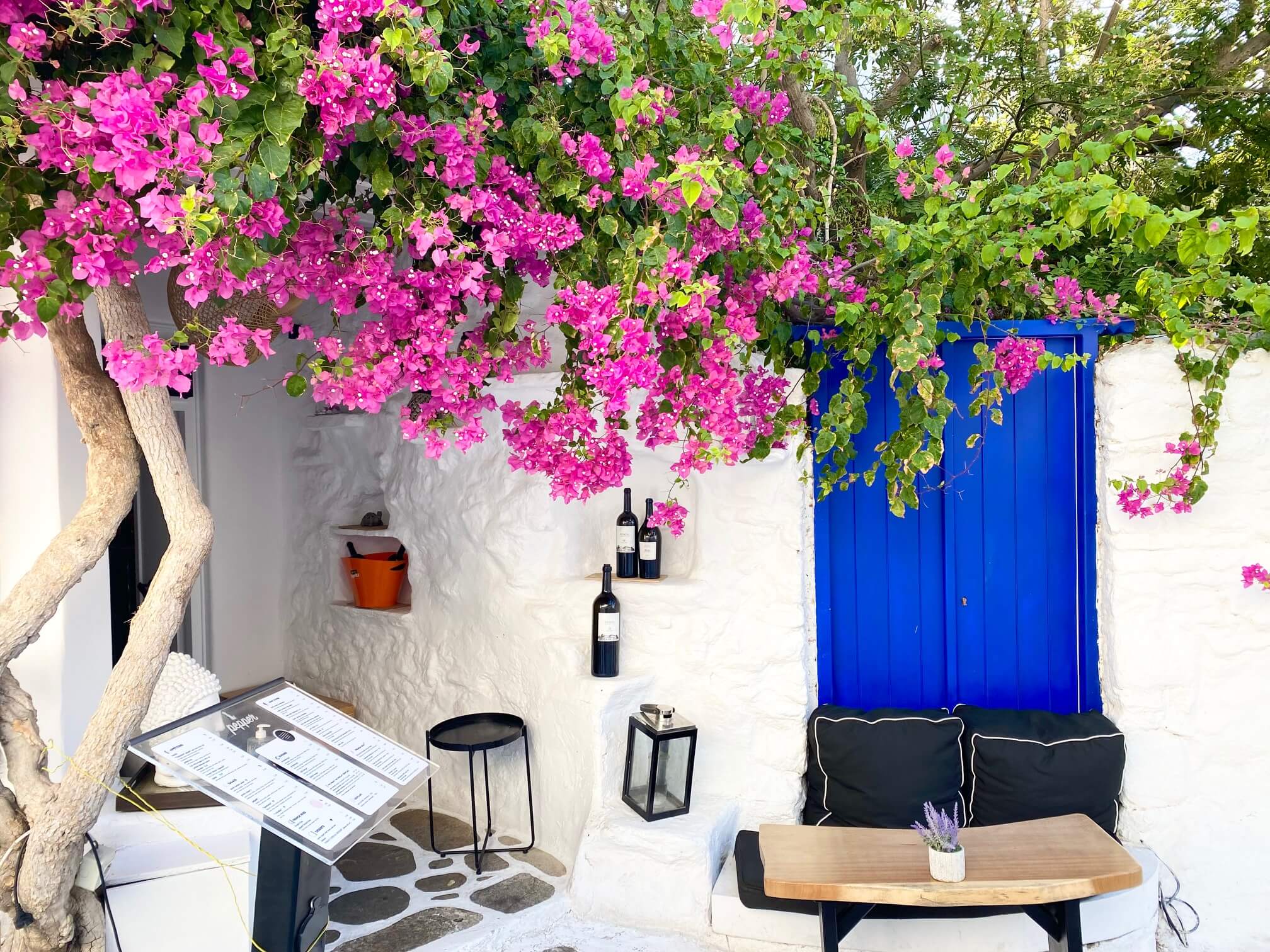 Restaurant entrance under a pink Bougainvillea in a whitewashed alley