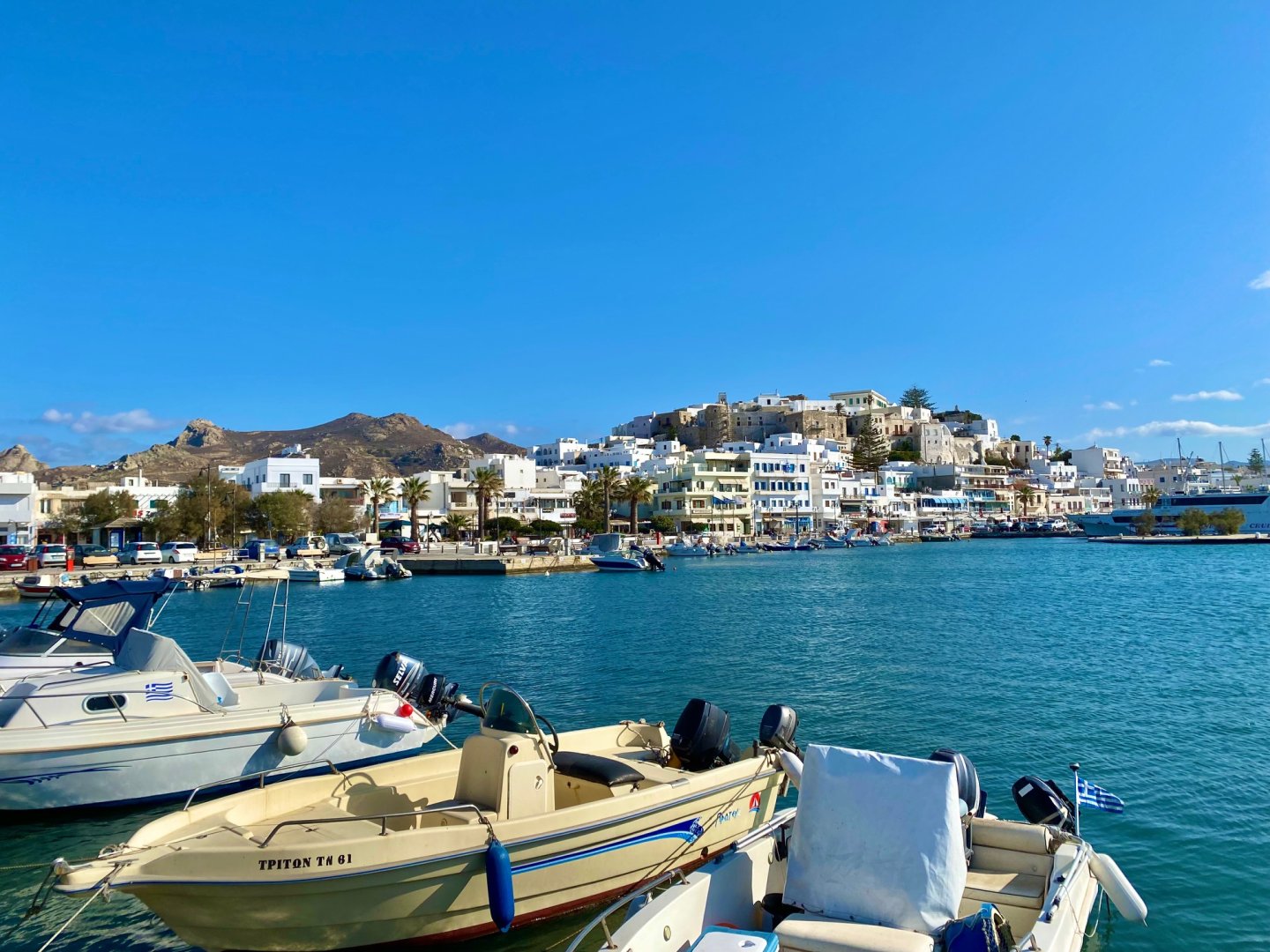 Small speed boats in the harbour with Chora Naxos on the hill behind