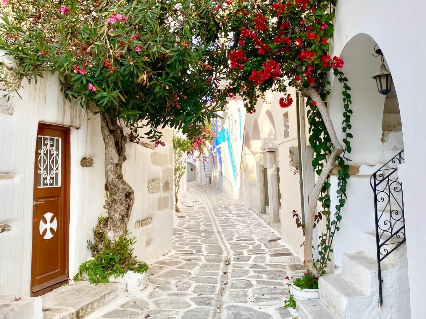 Narrow whitewashed village street with a church door and pin kand red bougainvillea