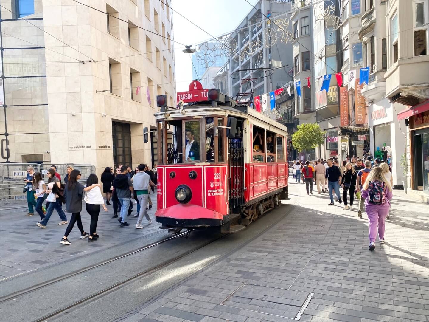 People walk either side of the vintage tram coming up Istiklal Street