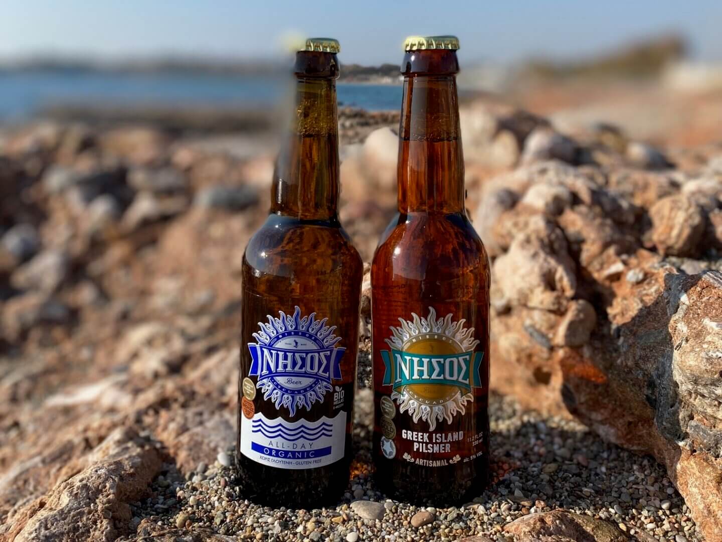Two Nissos beer bottles on rocks at the beach